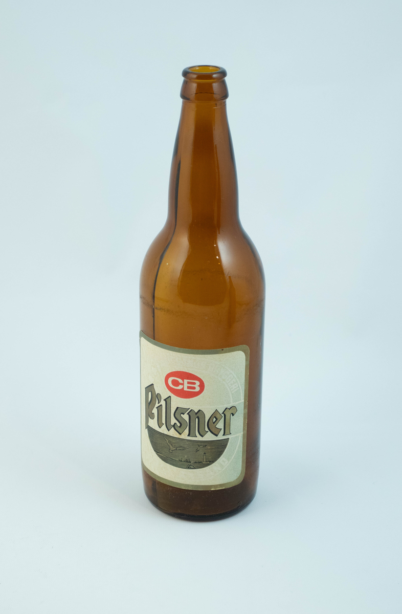 Brune glassflaskre med grønn papiretikett med hvit og lysebrun skrift. På den ene flasken er etiketten falmet hvit.