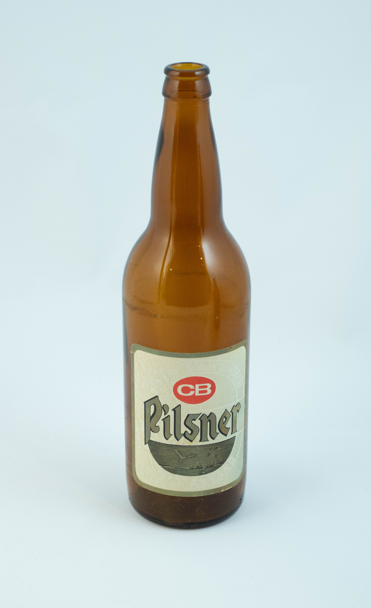 Brune glassflaskre med grønn papiretikett med hvit og lysebrun skrift. På den ene flasken er etiketten falmet hvit.