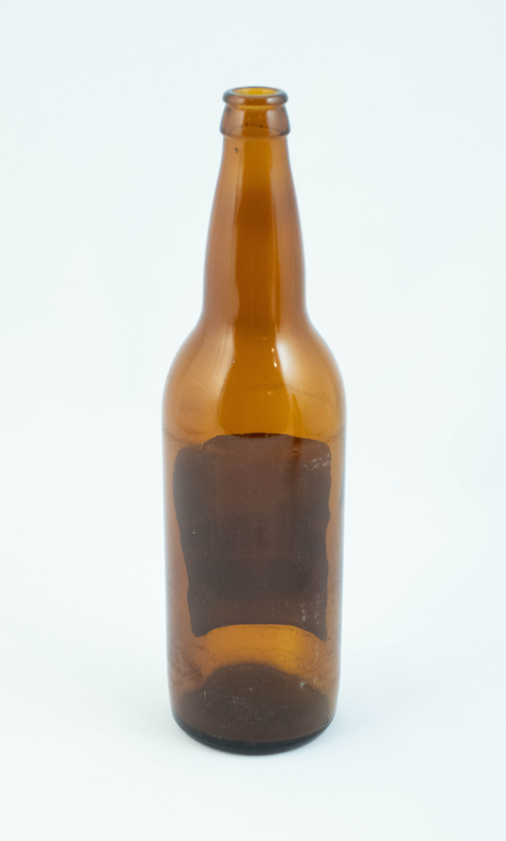 Brune glassflaskre med grønn papiretikett med hvit og lysebrun skrift. På den ene flasken er etiketten falmet hvit.
