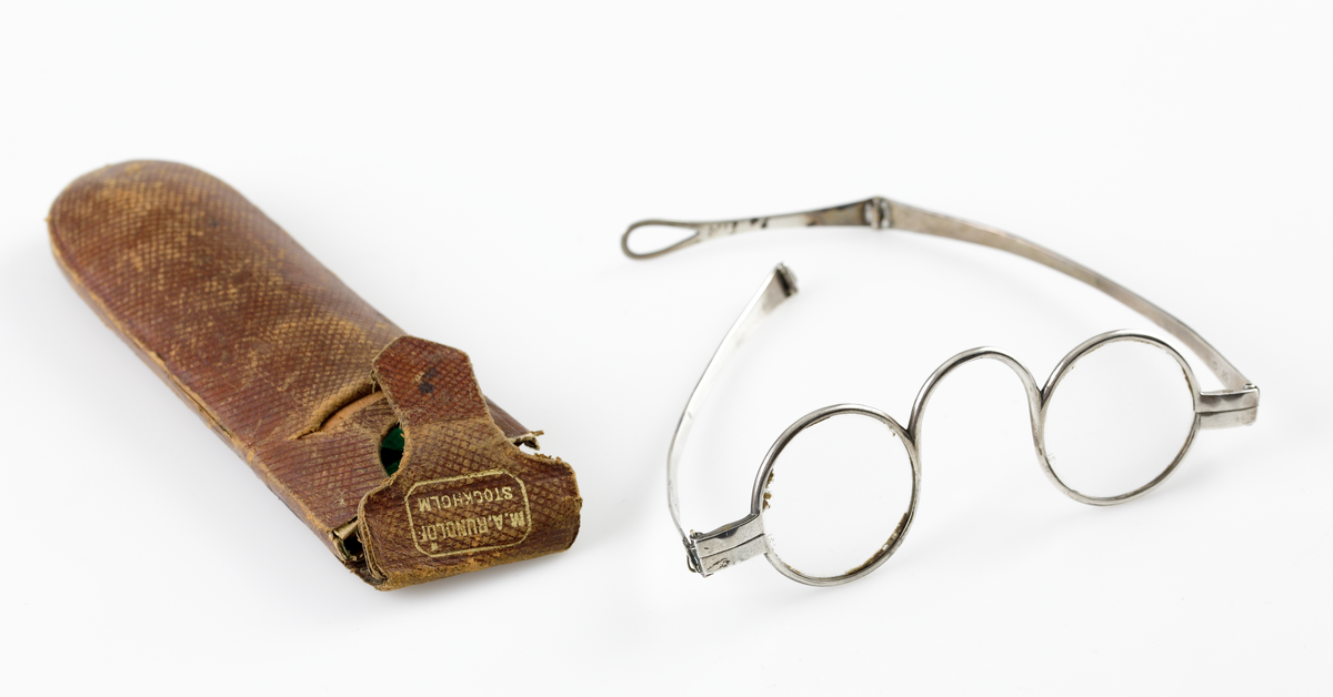 Ett par runda glasögon med skalmar av silver, 
Släta, ledade skalmar (höger ytterled saknas).
Förvaras i hårt, brunt läderetui. 

Inskrivet i huvudkatalogen 1944.