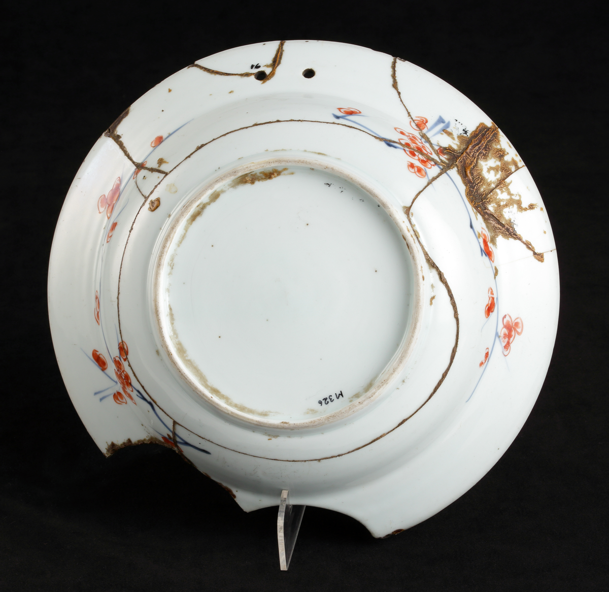 Rakfat av porslin.  Rund, med urgröpning nedtill. Två hål upptill (trol. för upphängning).
Polykrom heltäckande dekor, urna med blommor m.m. i rostrött, blått och grönt.

Inskrivet i huvudkatalogen 1886.