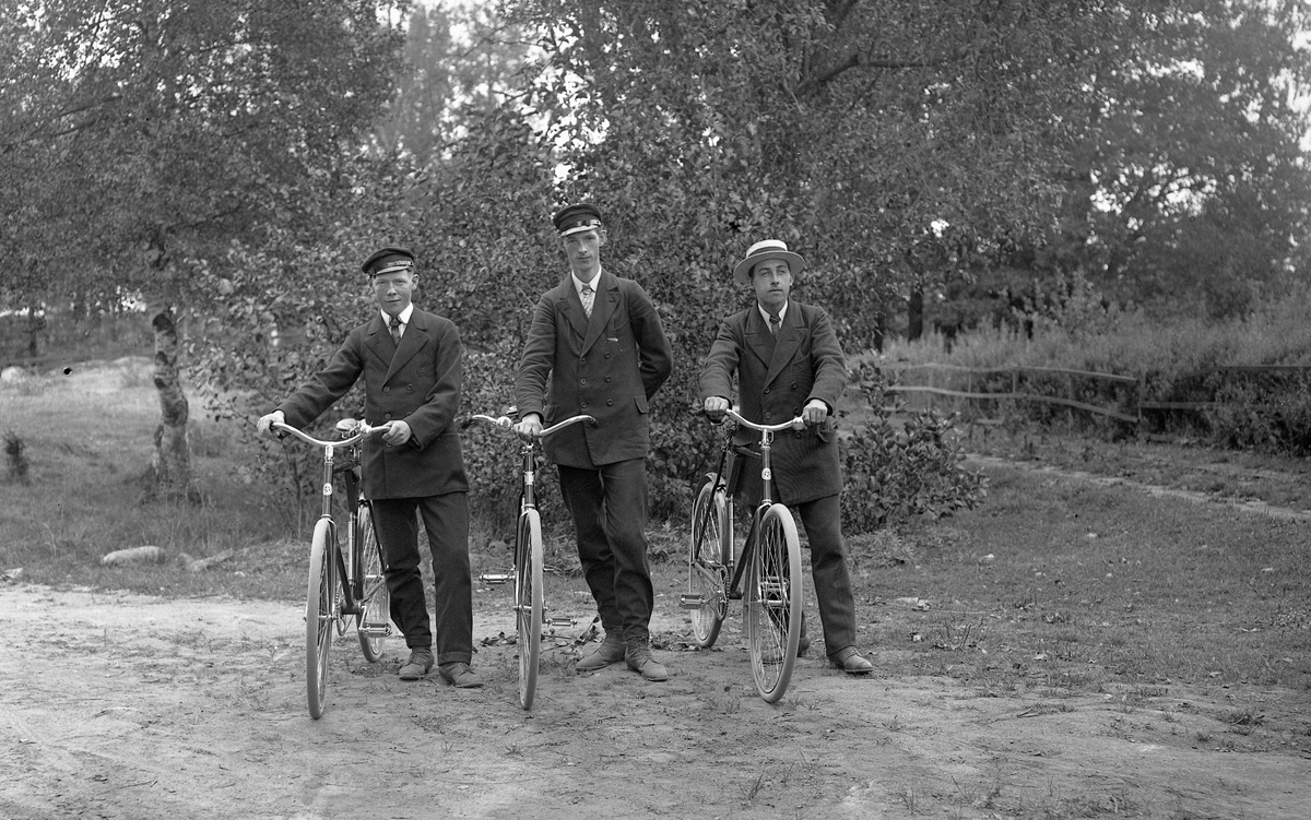 Tre unga män med cyklar