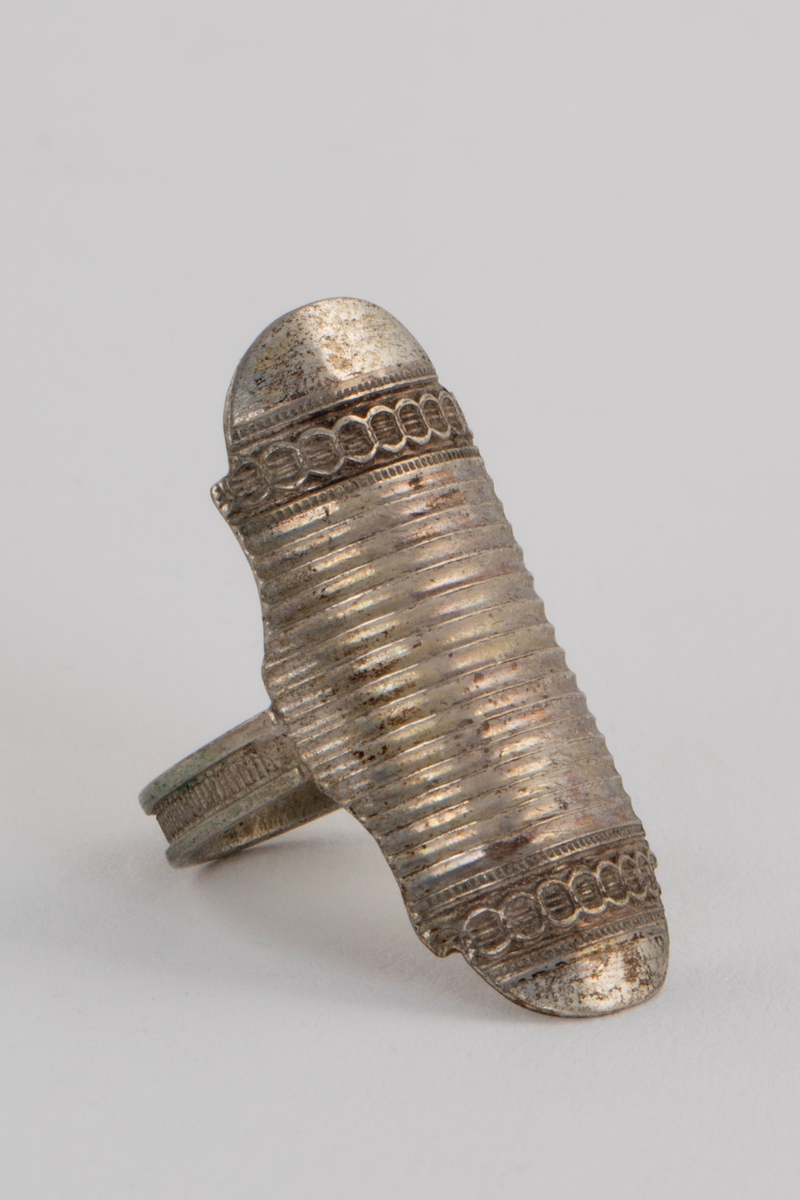 Sysett i etui, bestående av et nålehus og en fingerbeskytter i hvitt metall med dekor, og en fingerbøl med imitert filigran i forgylt metall. Settet ligger i et etui som på utsiden er trukket med rødt skinn, innvendig med hvit og rød silke og blå fløyel. Etuiet har også plass til en trenål, denne mangler.