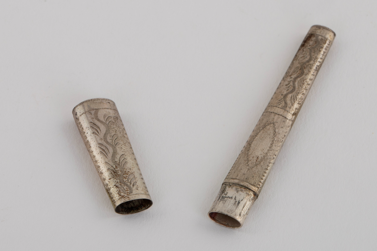 Sysett i etui, bestående av et nålehus og en fingerbeskytter i hvitt metall med dekor, og en fingerbøl med imitert filigran i forgylt metall. Settet ligger i et etui som på utsiden er trukket med rødt skinn, innvendig med hvit og rød silke og blå fløyel. Etuiet har også plass til en trenål, denne mangler.