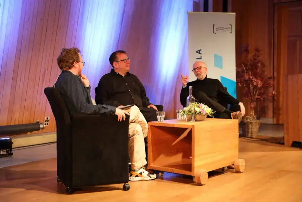 Tre menn i samtale på scene