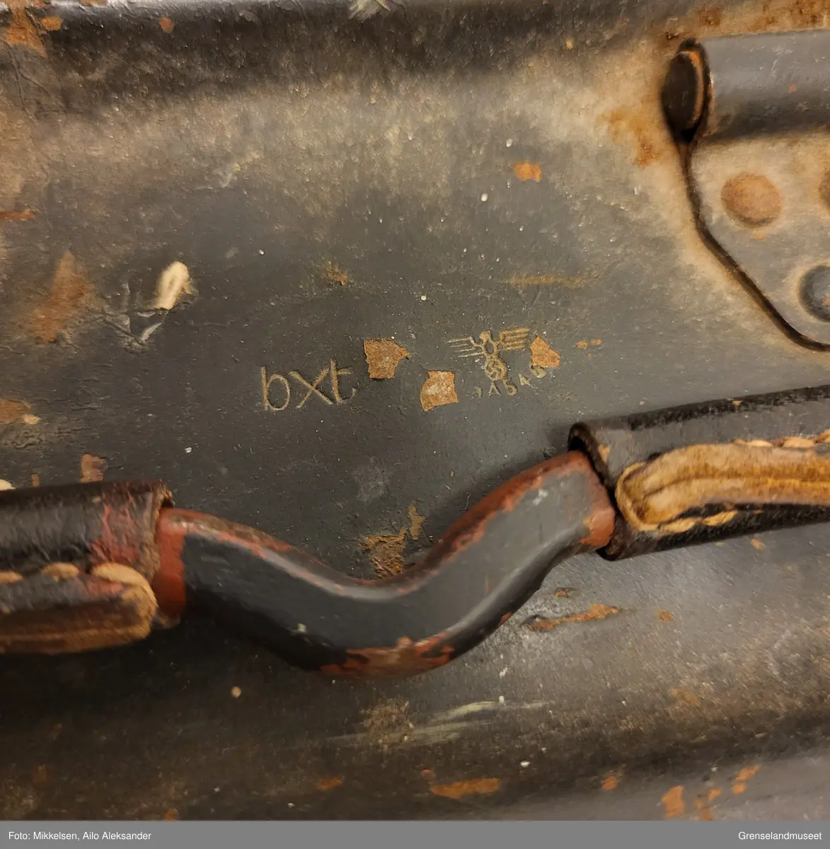 Gjenstanden er en svart malt ammunisjonskasse av jern metall som har vært brukt av tyske mitraljøsetropper under andre verdenskrig. Ammunisjonskassen har tre håndtak med sitt originale lærreimer til å dekke metallet. På venstre side over håndtak er åpne/lukke mekanismen til ammunisjonsboksen, den er i god stand og fungerer uten problemer. Innsiden av gjenstanden er blank og uten skader, bortsett fra litt rødt jern sverting. Bortsett fra riper, avskalling fra den svarte lakken og litt rød jern sverting, er gjenstanden i god stand  