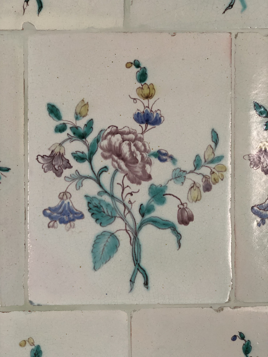 Flat kakelugn med avfasade hörn, uppsatt i rak form utan skänkhylla. Fotställning av trä i gustaviansk stil.