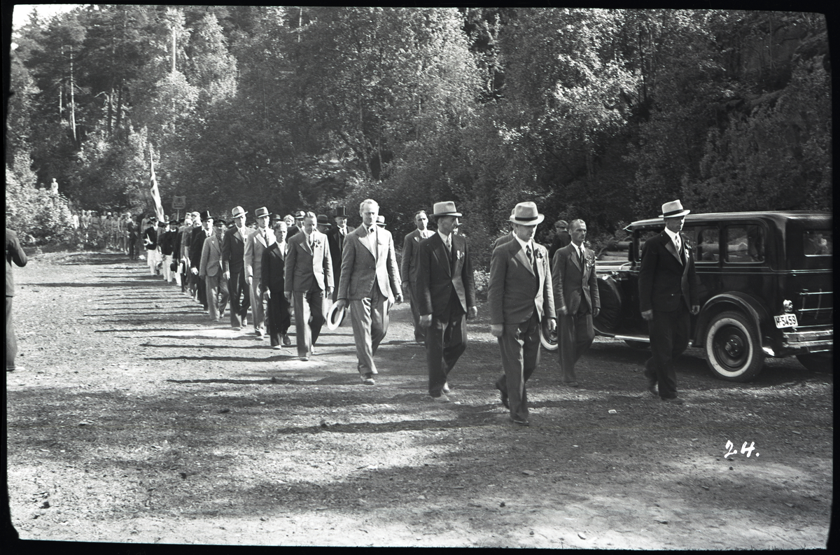 Foto av opptog i forbindelse med turnstevne på Skotfoss 1939

Bil til høyre har skiltnummer: H-5459

Påskrift på konvolutt: Turnstevnet, Skotfoss, 29/5 - 39