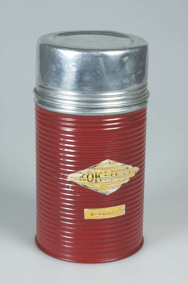 Mattermos av aluminium och järnplåt, rödlackerad med  skruvlock av metall. Två gula klistrade etiketter: INREGISTR: KOKHETT VARUMÄRKE samt STÅLGLAS. I botten text i relief: MADE IN SWEDEN BY TERMOVERKEN JÖNKÖPING. Inuti glas och kork.
