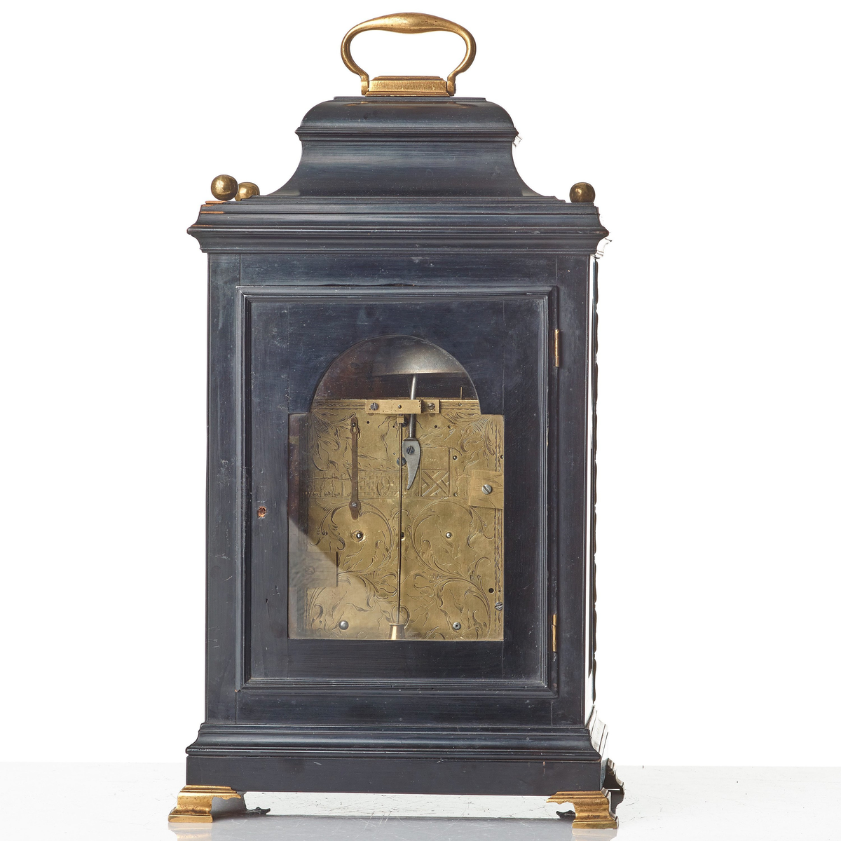 Bordspendyl med fodral av päronträ. Träytan är i vissa delar polerat för att efterlikna ebenholtz, men har även faner av ebenholts. Rektangulär form med rund urtavla. Överdelen är huvformad och har handtag av mässing. Överdelens hörn är dekorerade med knoppar av förgylld mässing. Urtavla med halvcirkelformat krön och visare för sekunder, i urtavlans hörn svickelornament av förgylld mässing. Den större urtavlan har visare för timmar och minuter med både arabiska och romerska siffror.  Båda urtavlorna har sifferringar med försilvring och förgyllda ytor. Nedtill profilerad sockel som vilar på kontursågade konsoler av mässing. Fodralet har på sidorna fram lister av mässing. Urfodralet har glasade sidor och glasat bakstycke.