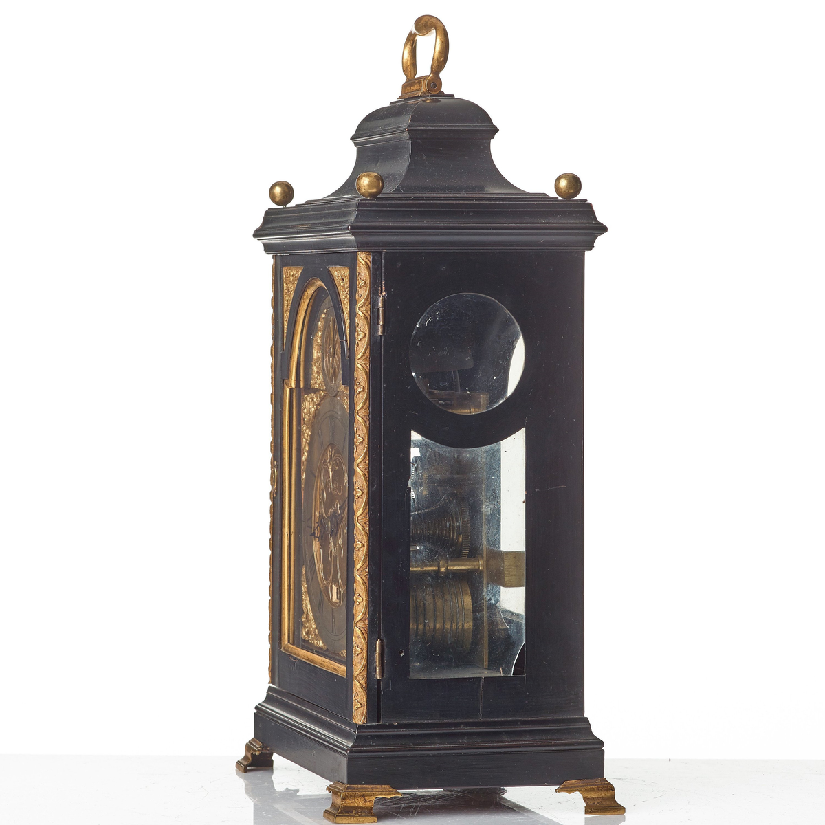 Bordspendyl med fodral av päronträ. Träytan är i vissa delar polerat för att efterlikna ebenholtz, men har även faner av ebenholts. Rektangulär form med rund urtavla. Överdelen är huvformad och har handtag av mässing. Överdelens hörn är dekorerade med knoppar av förgylld mässing. Urtavla med halvcirkelformat krön och visare för sekunder, i urtavlans hörn svickelornament av förgylld mässing. Den större urtavlan har visare för timmar och minuter med både arabiska och romerska siffror.  Båda urtavlorna har sifferringar med försilvring och förgyllda ytor. Nedtill profilerad sockel som vilar på kontursågade konsoler av mässing. Fodralet har på sidorna fram lister av mässing. Urfodralet har glasade sidor och glasat bakstycke.