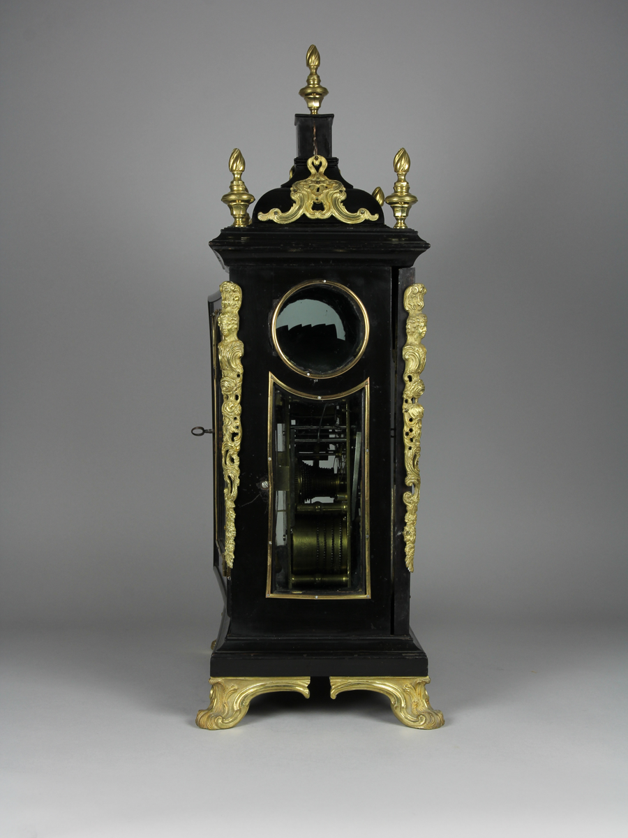 Bordsur med rektangulärt fodral av ebenholts och ek. Fodralet har upptill en överdel i form av en bruten kupol som är krönt med ett postament. Överdelen är dekorerad med beslag av förgylld brons. Beslagen är formade som rocailler och urnor med eldslågor. Fodralets framsida har en inglasad kvadratisk urtavla som avslutas upptill med halvcirkelformat krön. Krönet är flankerat av två fält med sågade ornament i trä. Urtavlan är rund med försilvrad yta. Visare för timmar och minuter samt kalender datum. Urtavla har både arabiska och romerska siffror. 

I hörnen brännförgyllda svickelornament i form av kartuscher. I urtavlans halvcirkelformade överstycke finns en mindre försilvrad urtavla och visare med graverad text "Strike" och "Silent" samt namn och adress för urmakaren. Den mindre urtavlan är omgiven av brännförgylld växtornamentik. Fodralets har fyra hörn som är dekorerade med ornament i förgylld brons formade som romerska soldater med plymer. Urets sidor har runda och rektangulära glasade fönster. Baksidan är glasad och visar en graverad tavla för pendel och klangskålar. Uret vilar på en sockel med förgyllda volutformade fötter. Urverk med flera olika klangskålar och förgyllda delar,