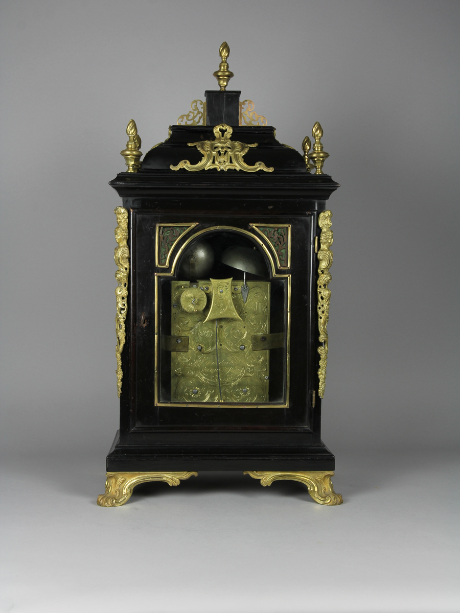 Bordsur med rektangulärt fodral av ebenholts och ek. Fodralet har upptill en överdel i form av en bruten kupol som är krönt med ett postament. Överdelen är dekorerad med beslag av förgylld brons. Beslagen är formade som rocailler och urnor med eldslågor. Fodralets framsida har en inglasad kvadratisk urtavla som avslutas upptill med halvcirkelformat krön. Krönet är flankerat av två fält med sågade ornament i trä. Urtavlan är rund med försilvrad yta. Visare för timmar och minuter samt kalender datum. Urtavla har både arabiska och romerska siffror. 

I hörnen brännförgyllda svickelornament i form av kartuscher. I urtavlans halvcirkelformade överstycke finns en mindre försilvrad urtavla och visare med graverad text "Strike" och "Silent" samt namn och adress för urmakaren. Den mindre urtavlan är omgiven av brännförgylld växtornamentik. Fodralets har fyra hörn som är dekorerade med ornament i förgylld brons formade som romerska soldater med plymer. Urets sidor har runda och rektangulära glasade fönster. Baksidan är glasad och visar en graverad tavla för pendel och klangskålar. Uret vilar på en sockel med förgyllda volutformade fötter. Urverk med flera olika klangskålar och förgyllda delar,