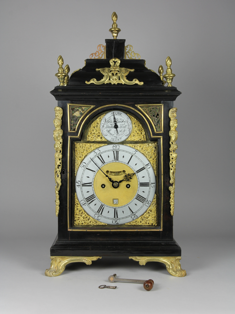 Bordsur med rektangulärt fodral av ebenholts och ek. Fodralet har upptill en överdel i form av en bruten kupol som är krönt med ett postament. Överdelen är dekorerad med beslag av förgylld brons. Beslagen är formade som rocailler och urnor med eldslågor. Fodralets framsida har en inglasad kvadratisk urtavla som avslutas upptill med halvcirkelformat krön. Krönet är flankerat av två fält med sågade ornament i trä. Urtavlan är rund med försilvrad yta. Visare för timmar och minuter samt kalender datum. Urtavla har både arabiska och romerska siffror. 

I hörnen brännförgyllda svickelornament i form av kartuscher. I urtavlans halvcirkelformade överstycke finns en mindre försilvrad urtavla och visare med graverad text "Strike" och "Silent" samt namn och adress för urmakaren. Den mindre urtavlan är omgiven av brännförgylld växtornamentik. Fodralets har fyra hörn som är dekorerade med ornament i förgylld brons formade som romerska soldater med plymer. Urets sidor har runda och rektangulära glasade fönster. Baksidan är glasad och visar en graverad tavla för pendel och klangskålar. Uret vilar på en sockel med förgyllda volutformade fötter. Urverk med flera olika klangskålar och förgyllda delar,