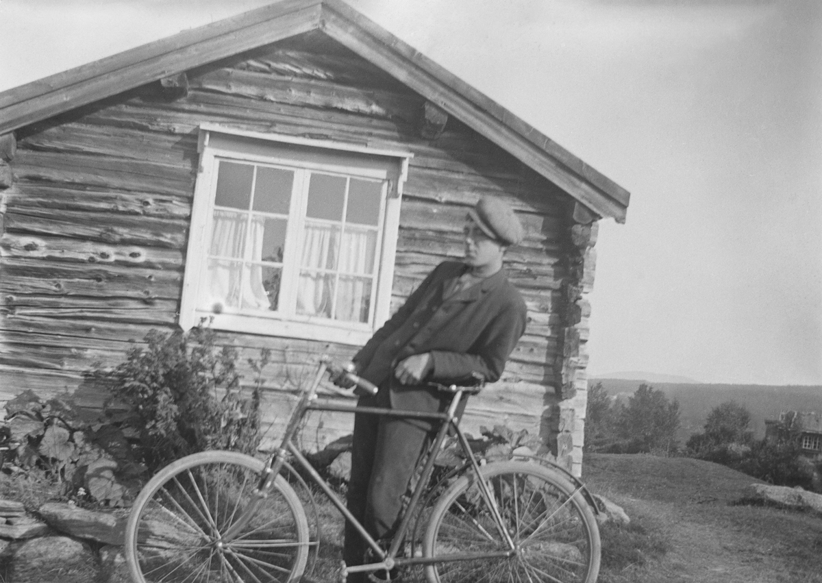 Mann med sykkel ved stuebygning





