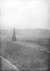 Dame med hatt. Bybebyggelse i bakgrunnen