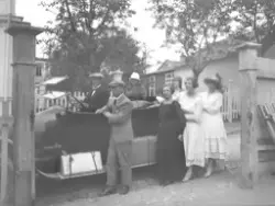 Personer ved  og i en bil. Bymiljø.