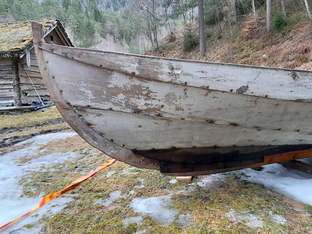 Båt. Kyrkjebåt. Klinkbygd trebåt. 4 omfar. Firrøing. For årar og segl. Kvitmåla utvendig, invendig måla mørk gråleg. Restar av raudmåla, tynn stripe langs ripa oppå og på utsida. Delar av m.a. kjøl og botnabord utskifta i nyare tid (umåla).