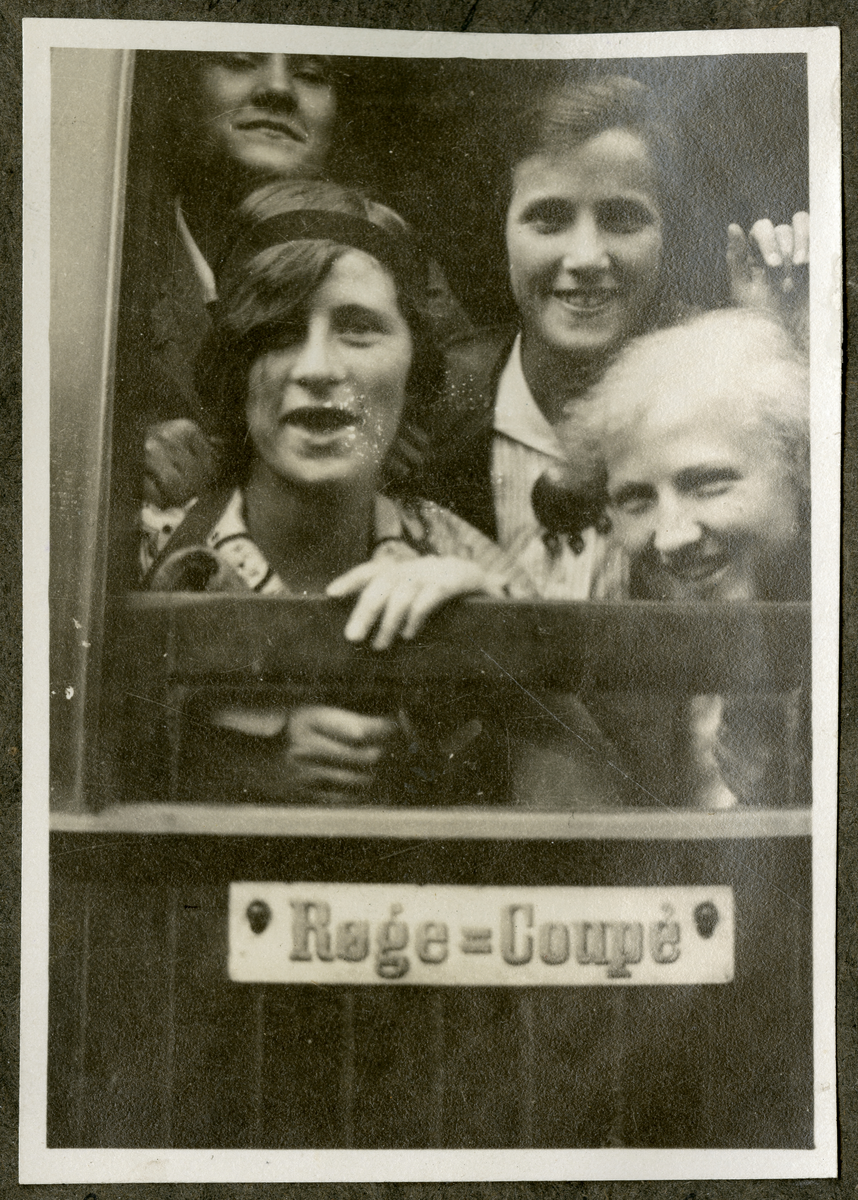 Portrett av ukjente kvinner som smiler til kamera i fra en røykekupee på et tog i 1915

Påskrift i album: 

"Røkning forbudt"
Starten til Krokkleven 19/6-1915

Skilt på togvognen: Røge-coupe