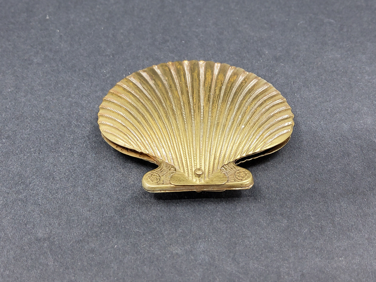 NÅLBREVSETUI ELLER GÖMMA, AV MÄSSING I FORM AV MUSSLA, UTFÄLLBAR HÅLLARE FÖR NÅLBREV INUTI MUSSLAN.  ORNERAT.