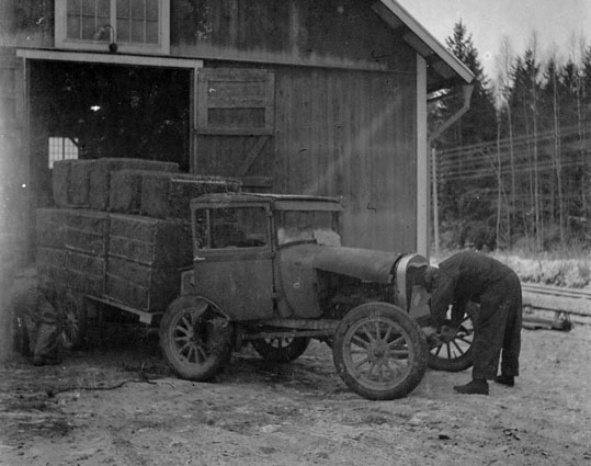 En man vevar igång en märklig gammal bil med lastkärra.