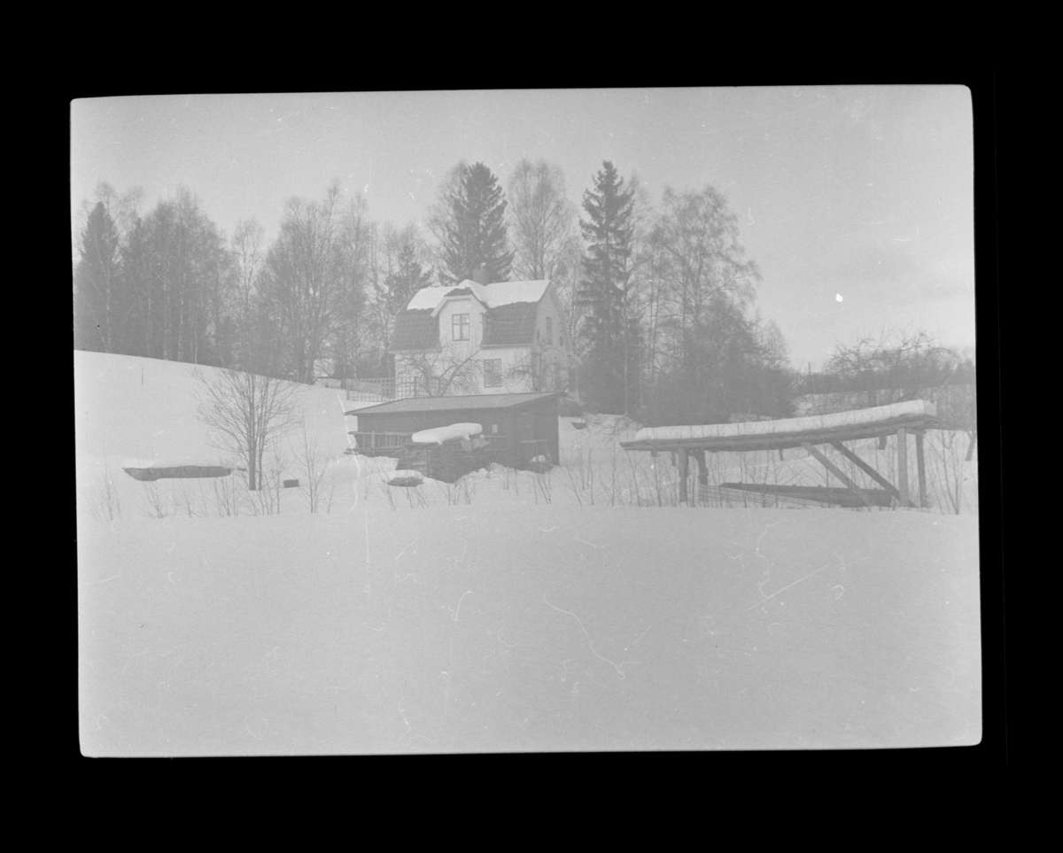 Villa och uthus i vinterlandskap.