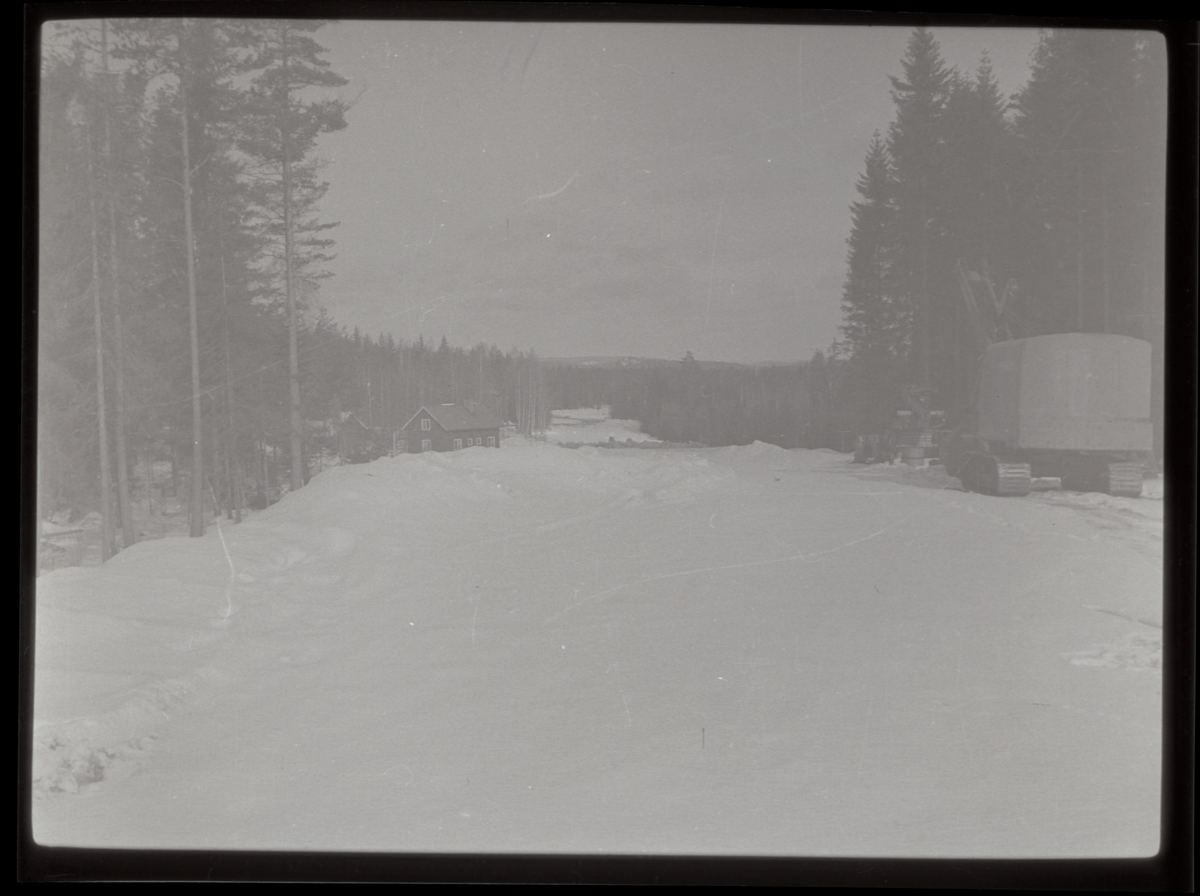 Grävmaskin och villa i vinterlandskap.