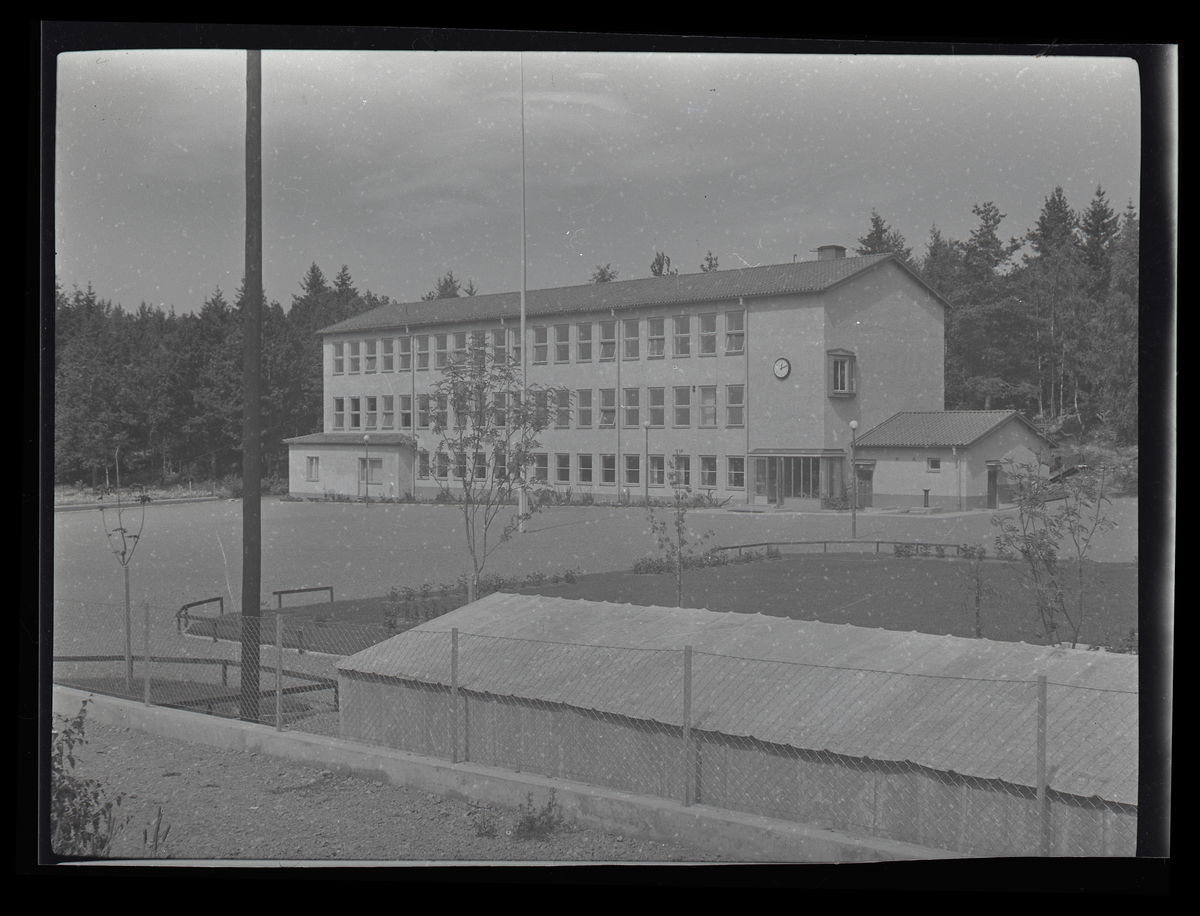 Skolbyggnad med idrottsplan i fögrunden.