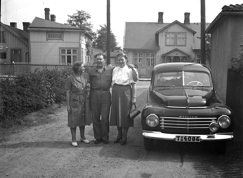 Två kvinnor och en man står bredvid en Volvo PV.