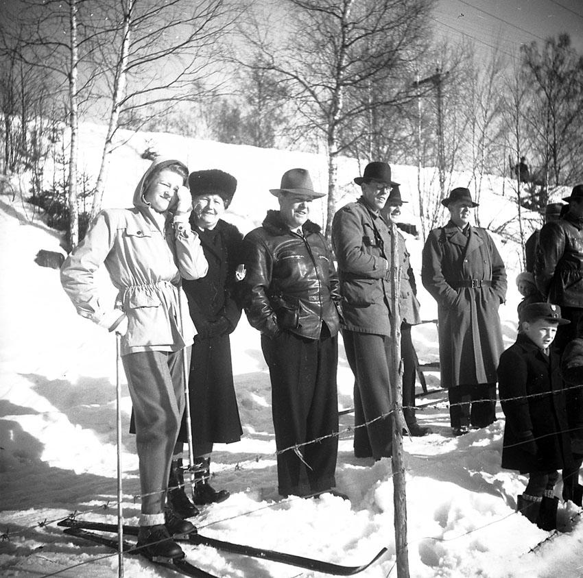 Ett antal personer ute i vinterlandskapet, varav en med skidor.