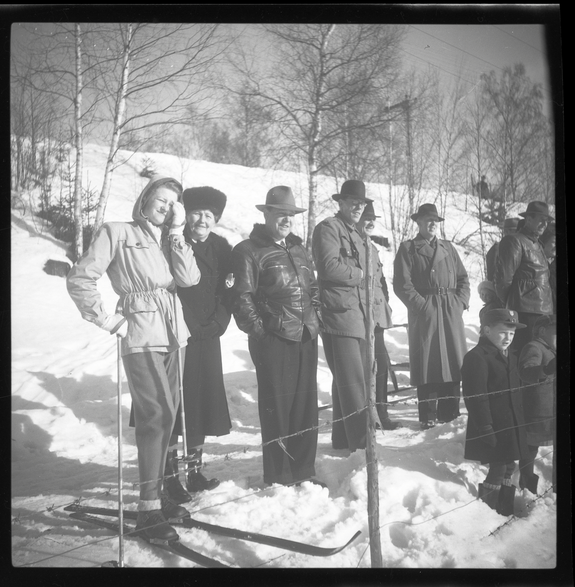 Ett antal personer ute i vinterlandskapet, varav en med skidor.