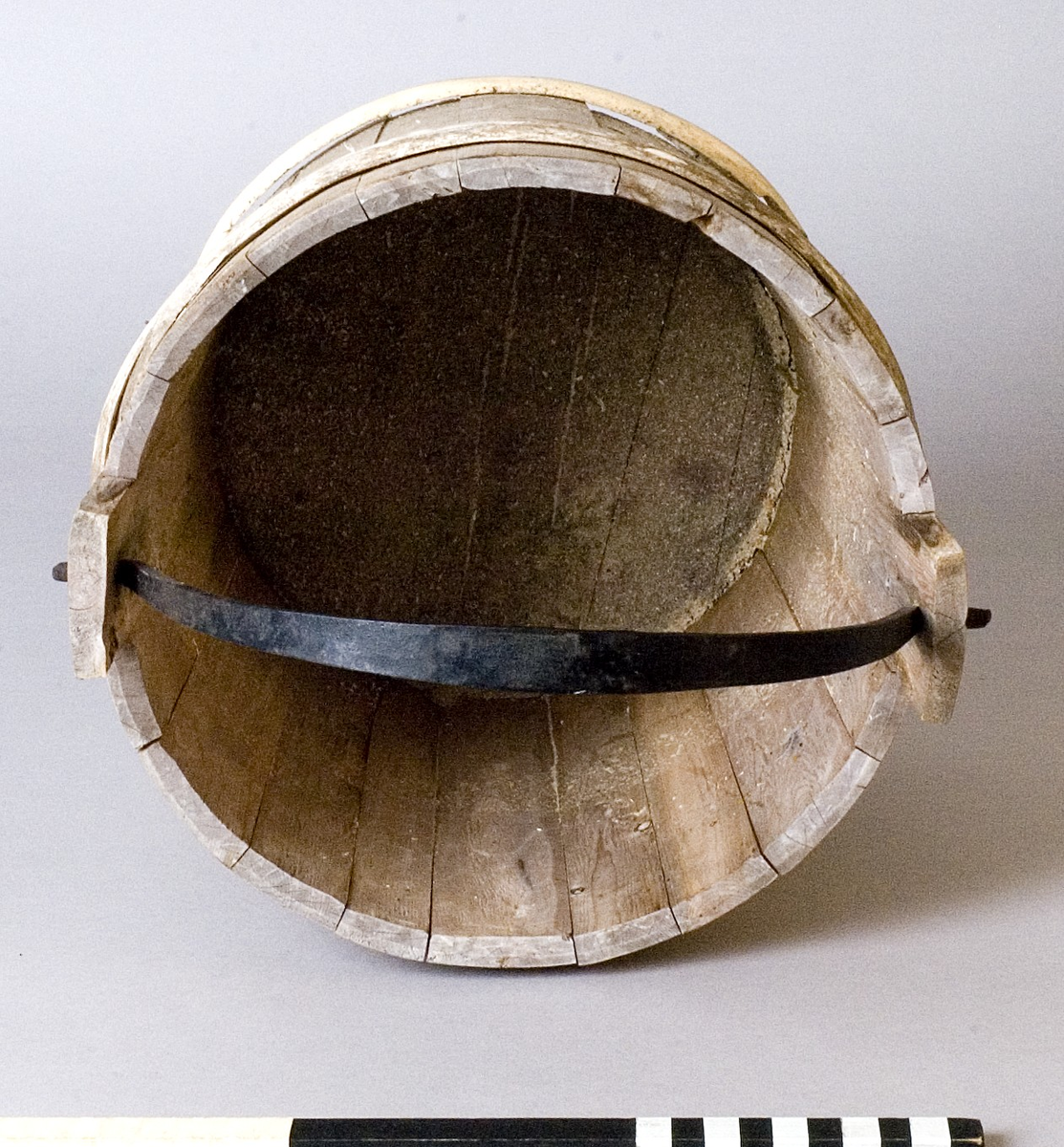 Spann av trä med smitt handtag av järn. Spannen utförd i laggteknik och hålls samman med två band av eneträ.