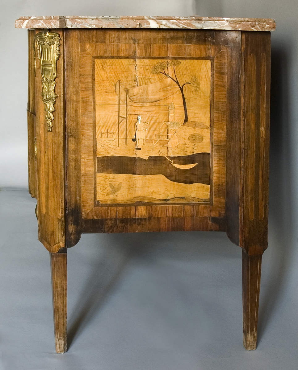 På framsidan dekor i intarsia med tre olika figurscener, inramade i rutor med markerade hörn. I mittfältet en sittande kines på en upphöjning under en genombruten baldakin omgiven av två män i västerländsk dräkt som spelar och sjunger. Två flankerande träd, i förgrunden ett vattendrag med två båtar och några män med tunnor. De vita ansiktena är inlagda med ben. Sidofälten har (enligt katalogkortet) emblem för krigisk idrott (till vänster) och fredlig idrott (till höger).
På byråns båda sidor samma motiv: en kvinna under en baldakin av tyg, ett träd, en antydd byggnad och ett vattendrag med en båt.