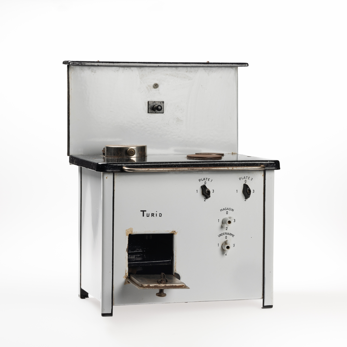 Miniatyrutgave av magasinkomfyr fra KPS. Komfyren har 2 plater, samt ett magasin og stekovnsfunksjon med undervarme. 

Denne komfyren ble spesiallaget  på fritiden av en arbeider ved KPS. Den ble laget til datteren i huset der han hadde husvære (Turid). Han skal også ha laget en til direktørens datter. Borgarsyssel har en maken miniatyrkomfyr som er stemplet KPS - se BrM.11021.