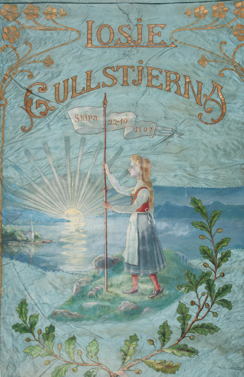 Jente i bunad, vimpel, oppstigande sol, landskap, sjø, eikegreiner med lauv.