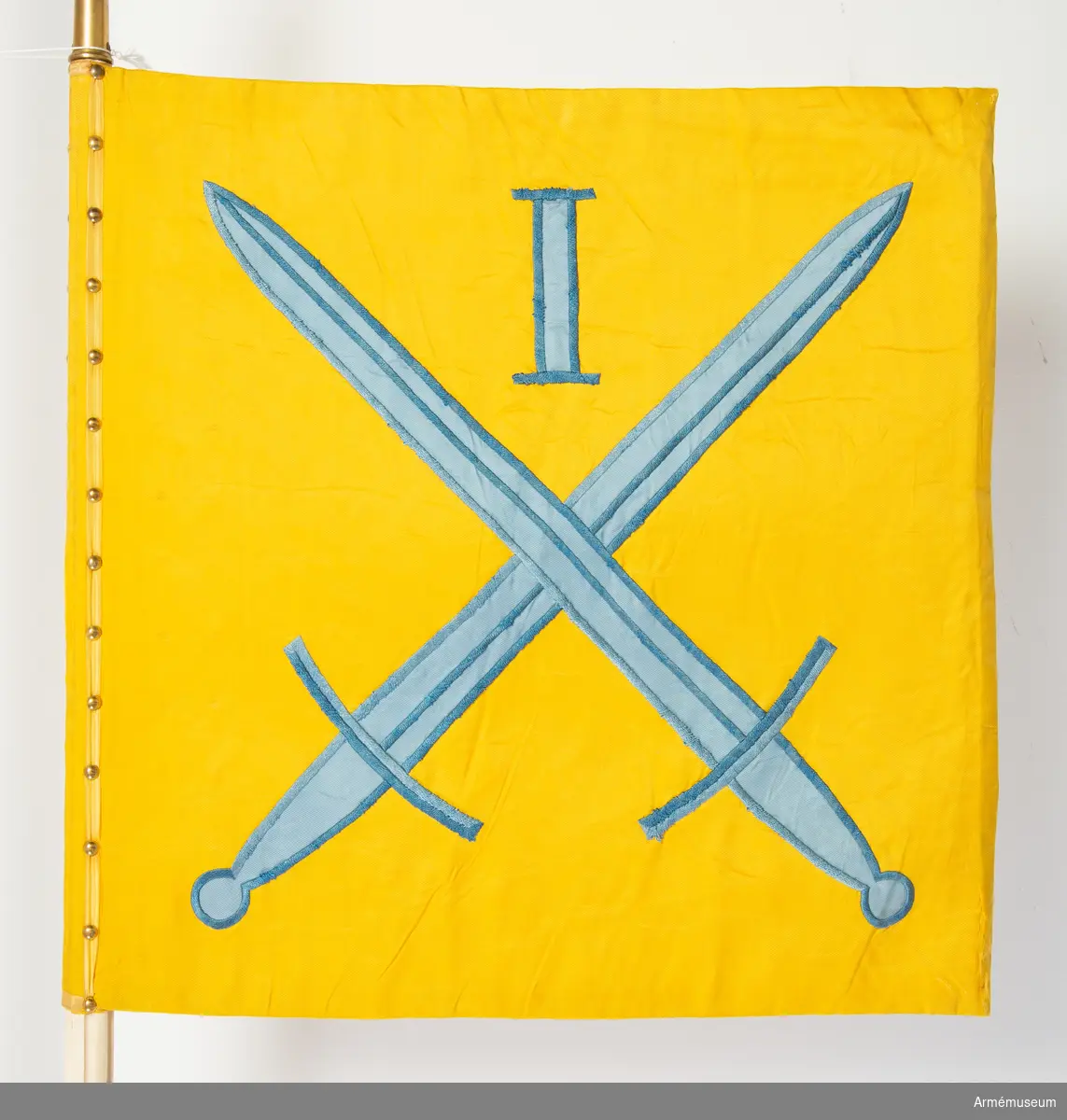 Kommandotecken för Södra militärområdet (ursprungligen Första militärområdet), i gult siden med applikation i blått siden med broderi i blått silkegarn.
På gul botten två blå korslagda svärd under den romerska siffran 1. Vit stång med kannelyrer och spets av mässing.