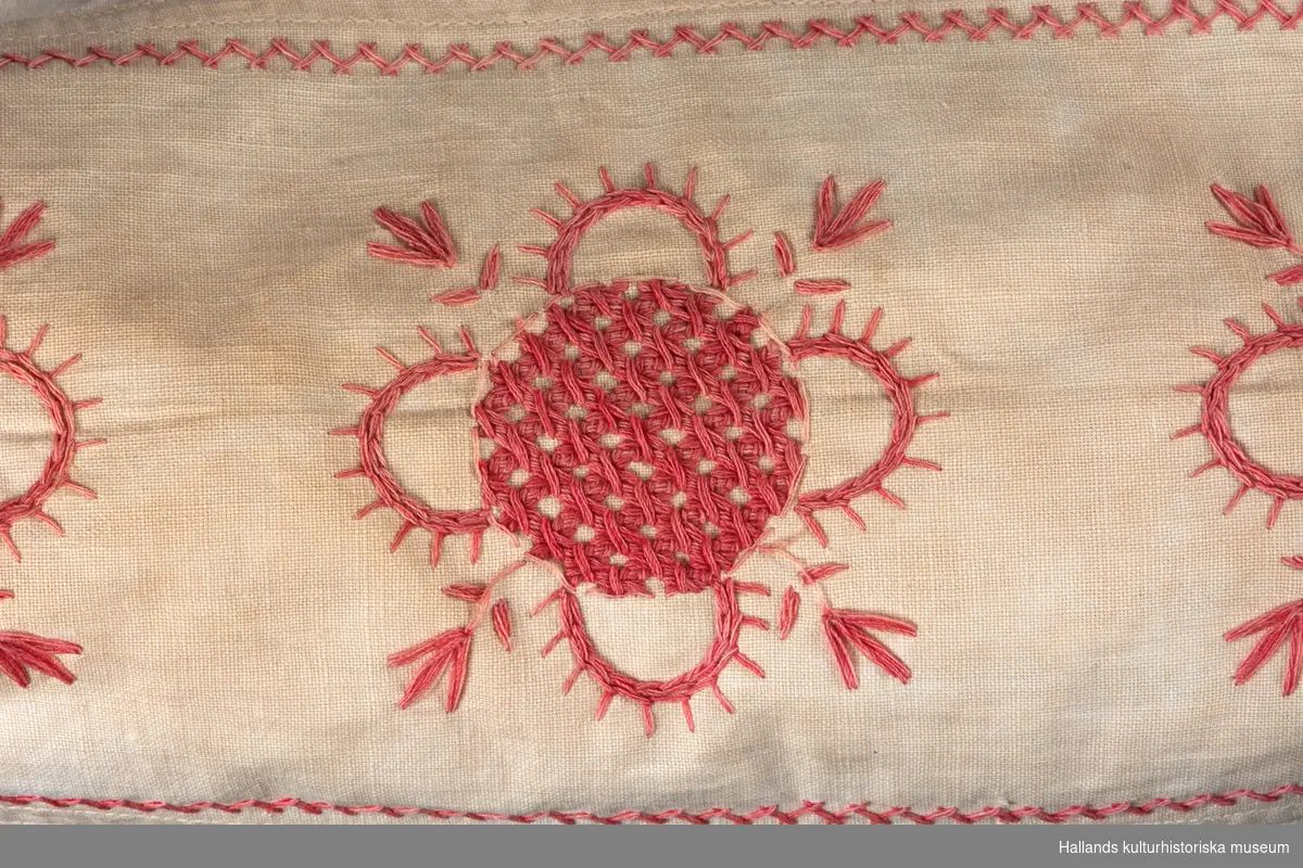 Örngott av vävt bomullstyg med klädda knappar i öppningen. Kanten utmed öppningen ör sydd med hålsöm. Ena sidan broderad med röd hallandssöm  Broderade initialer: "CB" i jugendstil.