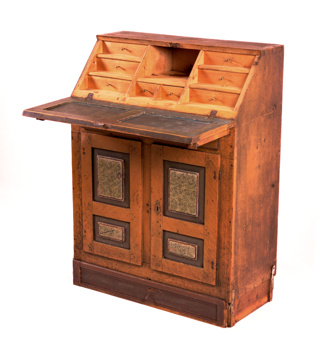 Skatholl med skuff over og under dobbel dør. Inndela med 8 små skuffar og eit ope rom bak skriveklaff. Lås og nykil til dør og til skriveklaff. Ådringsmåla.