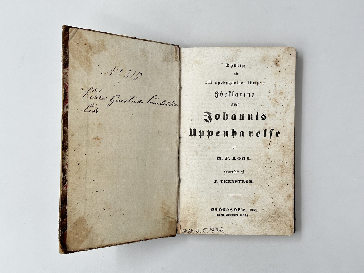 Bok: "Förklaring öfwer Johannis Uppenbarelse". Rygg samt omslagets hörn i skinn. Omslaget i brun, marmorerad kartong. Samlingsnumrering Väla sockenbibliotek Nr 215.