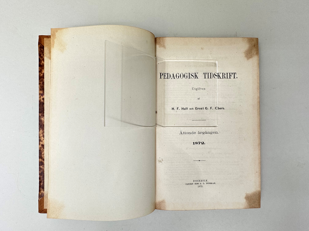 Bok: "Pedagogisk tidskrift 1872". Tryckt 1872 i Stockholm.
Halvfranskt band. Rygg av cognacsfärgat läder med förgyllda nedsänkta bokstäver och rader. Hörn förstärkta med läder. Pärm av kartong klädd i fläckmarmorerat papper i brunt och gult.