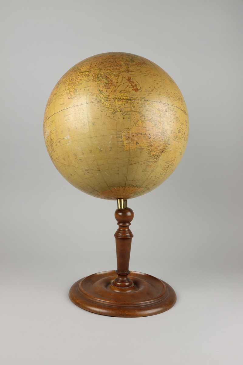 Jordglob av metall och papper med ett stativ i valnötsträ, samt lutande axel. På globen mitt upp en mässingsknopps pol. Stativets svarvade pelare är fäst i globen med en arm av mässing och avslutas med en svarvad rund fot. Upptill mot polen en etikett med röd text i versaler "Cohrs jordglob".