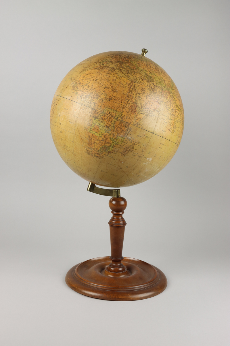 Jordglob av metall och papper med ett stativ i valnötsträ, samt lutande axel. På globen mitt upp en mässingsknopps pol. Stativets svarvade pelare är fäst i globen med en arm av mässing och avslutas med en svarvad rund fot. Upptill mot polen en etikett med röd text i versaler "Cohrs jordglob".