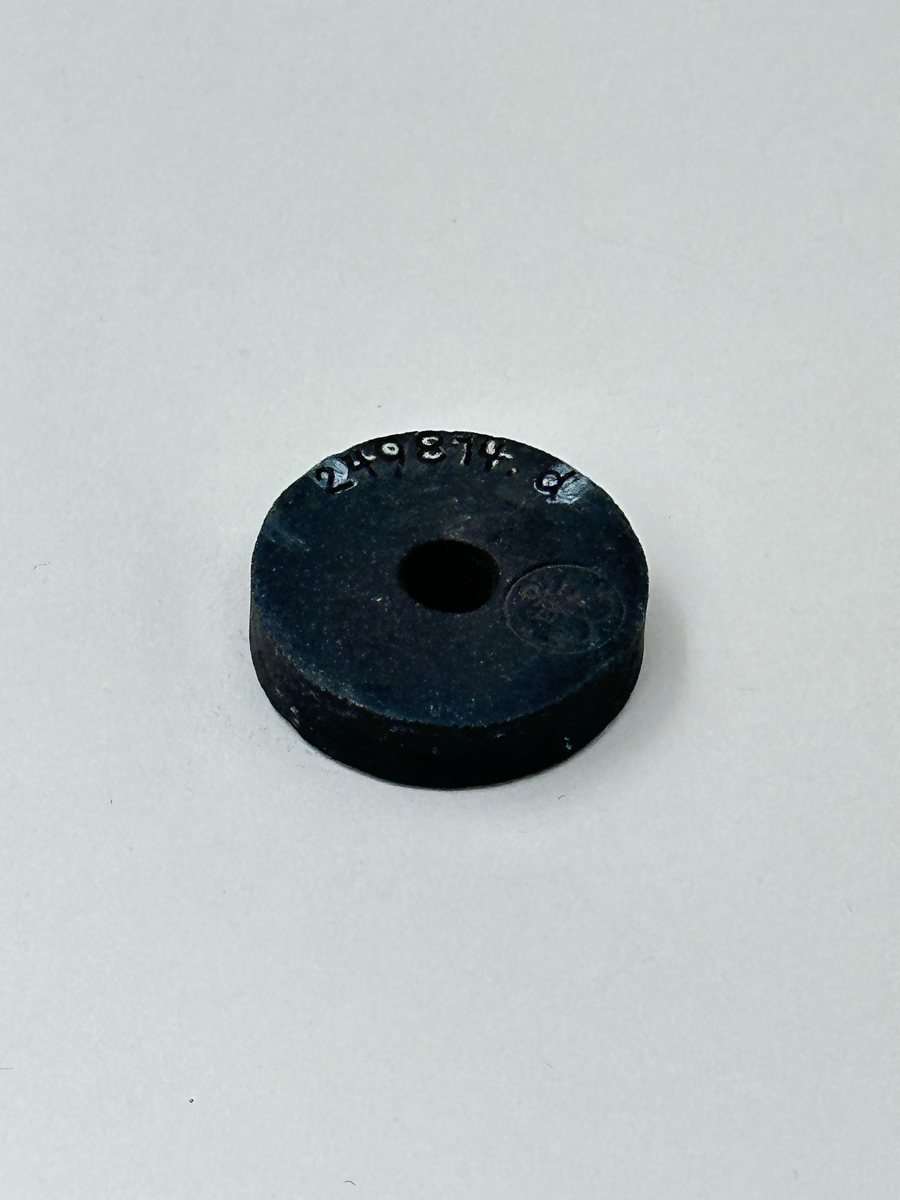 Lösa delar till symaskin, 19 till antalet. Bland annat pressarfötter, en svart ring med hål i mitten samt diverse andra platta metalldelar. 
