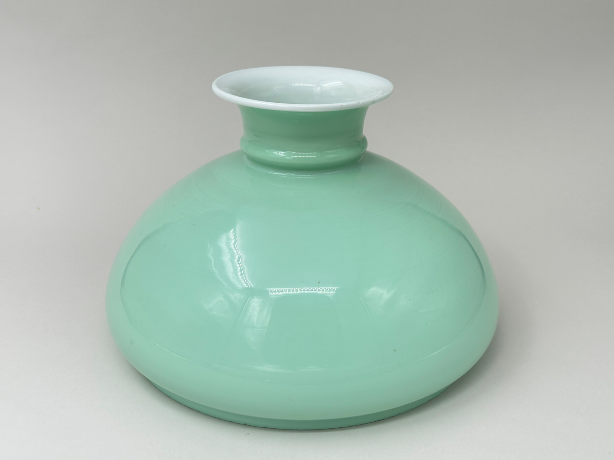 Lampskärm av vesta-typ till fotogenlampa. I opakt glas, vit på insidan, mintgrön på utsidan. 