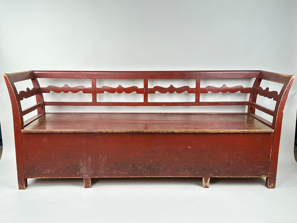 Kökssoffa i gran. Rödmålad. Rak rygg delad i fyra sektioner med en vågig tvärbricka mellan varje sektion. Armstöden något utåtsvängda med motsvarande tvärbricka. Fyrkantiga låga ben. Lock bestående av två brädor, avtagbart. Soffan ursprungligen utdragbar, senare fastskruvad i infällt läge. Insidan obehandlad. Senare förstärkt invändigt med en obehandlad bräda skruvad i soffans bakkant. Den utdragbara delen har två låga ben i framkant.