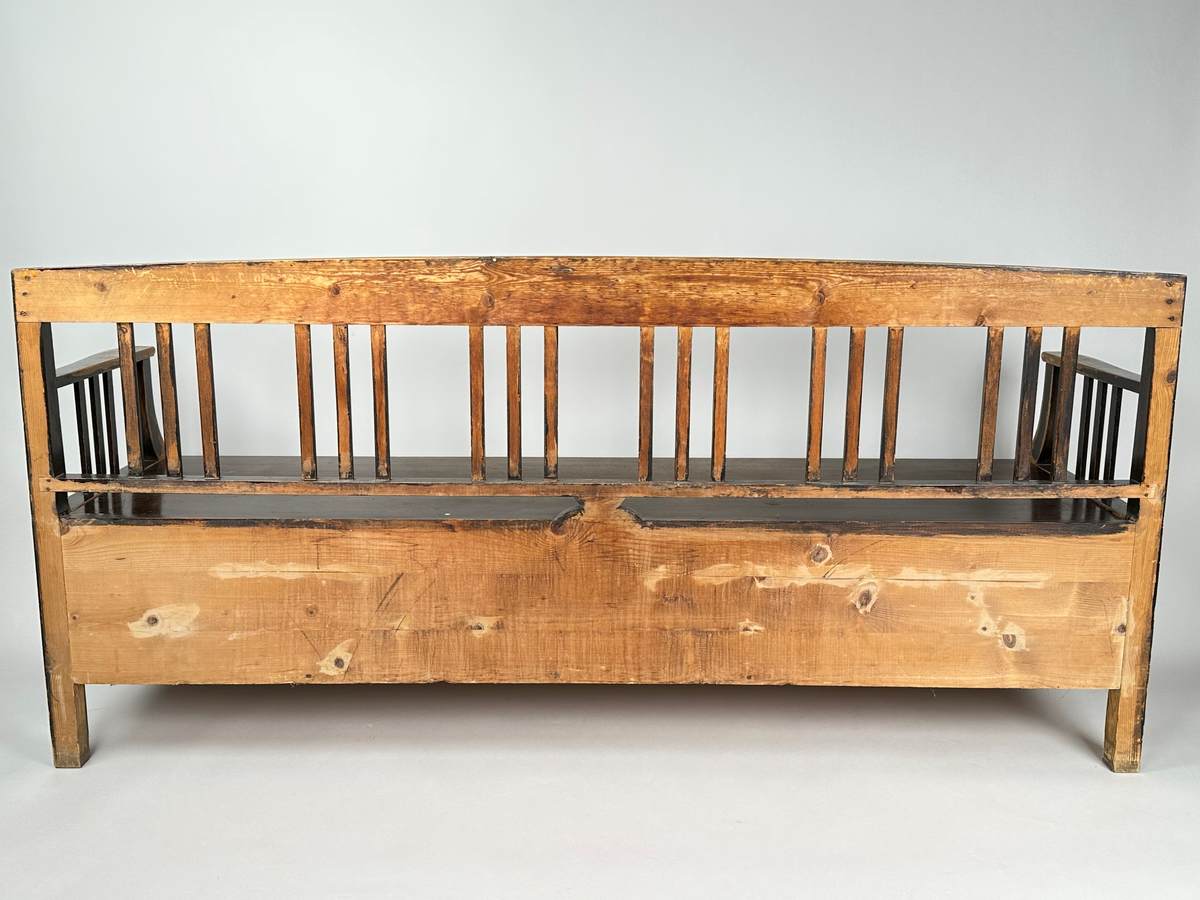 Kökssoffa i ådringsmålat trä. Välvd spjälrygg bestående av sex grupper av tre spjälor i varje. Armstöd med tre spjälor samt en svängd främre stolpe som övergår i soffans framben i respektive hörn. Lock bestående av två brädor, avtagbart. Soffan utdragbar, insidan obehandlad. Den utdragbara delen har två lätt konade ben i framkant.