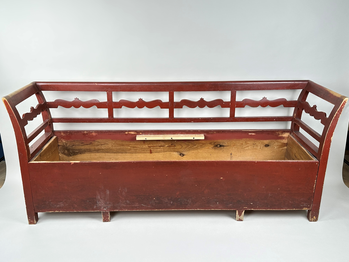 Kökssoffa i gran. Rödmålad. Rak rygg delad i fyra sektioner med en vågig tvärbricka mellan varje sektion. Armstöden något utåtsvängda med motsvarande tvärbricka. Fyrkantiga låga ben. Lock bestående av två brädor, avtagbart. Soffan ursprungligen utdragbar, senare fastskruvad i infällt läge. Insidan obehandlad. Senare förstärkt invändigt med en obehandlad bräda skruvad i soffans bakkant. Den utdragbara delen har två låga ben i framkant.