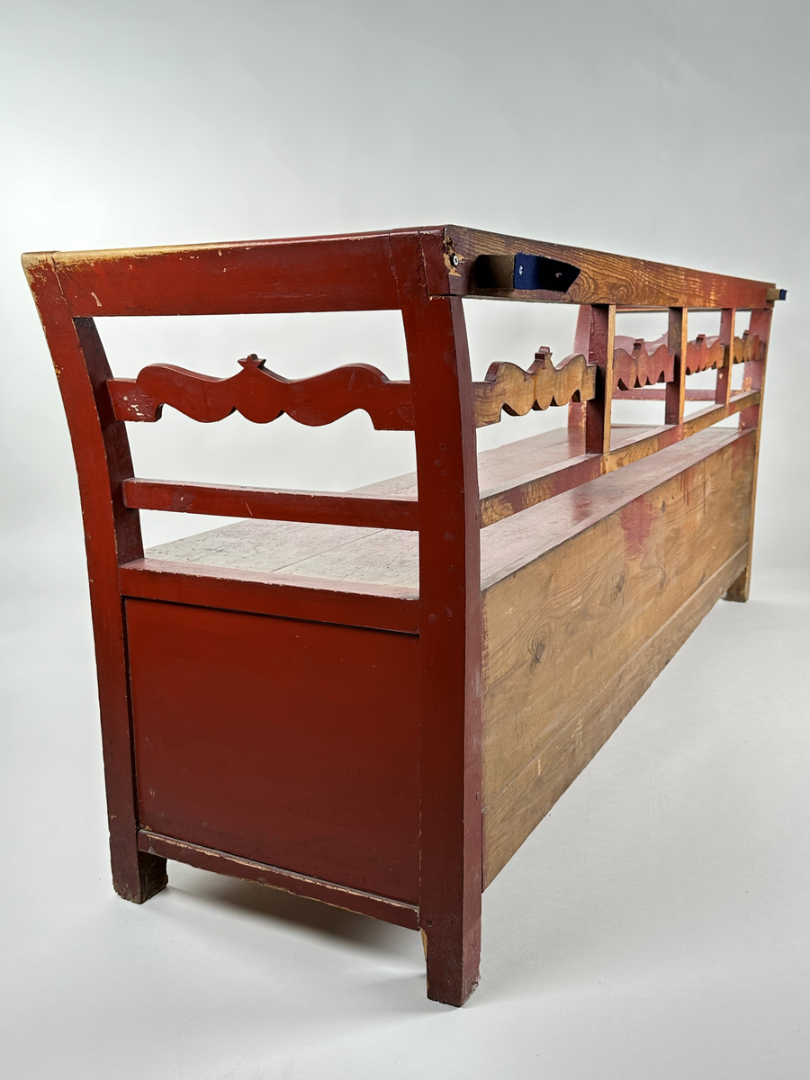 Kökssoffa i gran. Rödmålad. Rak rygg delad i fyra sektioner med en vågig tvärbricka mellan varje sektion. Armstöden något utåtsvängda med motsvarande tvärbricka. Fyrkantiga låga ben. Lock bestående av två brädor, avtagbart. Soffan ursprungligen utdragbar, senare fastskruvad i infällt läge. Insidan obehandlad. Senare förstärkt invändigt med en obehandlad bräda skruvad i soffans bakkant. Den utdragbara delen har två låga ben i framkant.