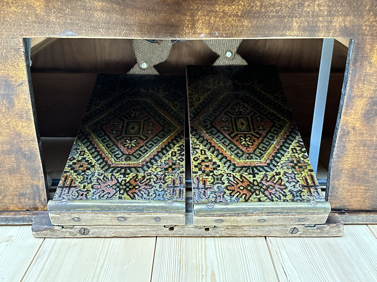 Orgel, tramporgel. Av mörk betsad och lackerad björk, samt svartmålad baksida. Profilerade sidostycken med målade svarta kanter. Dekorativt utformade ljudhål, som linjer med cirkulära avslut. Fäll- och låsbart lock med fastmonterad fällbar notställslist. Tangenter av trä med fanér på de vita tangenterna av ben el. horn. Två pedaler, klädda med sekundär, orientaliskt mönstrad och lackad korkmatta.