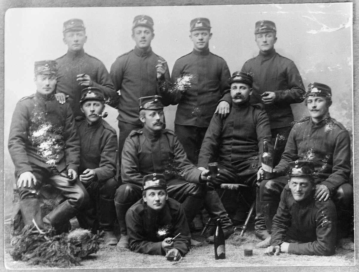 Gruppebilde av soldater på Gardermoen ca. 1905. Ole P. Fjørkenstad er nr. tre fra venstre. Han sitter på ryggen til en av kameratene, og med et ølglass i hånda. Han var ved "dragonen".
